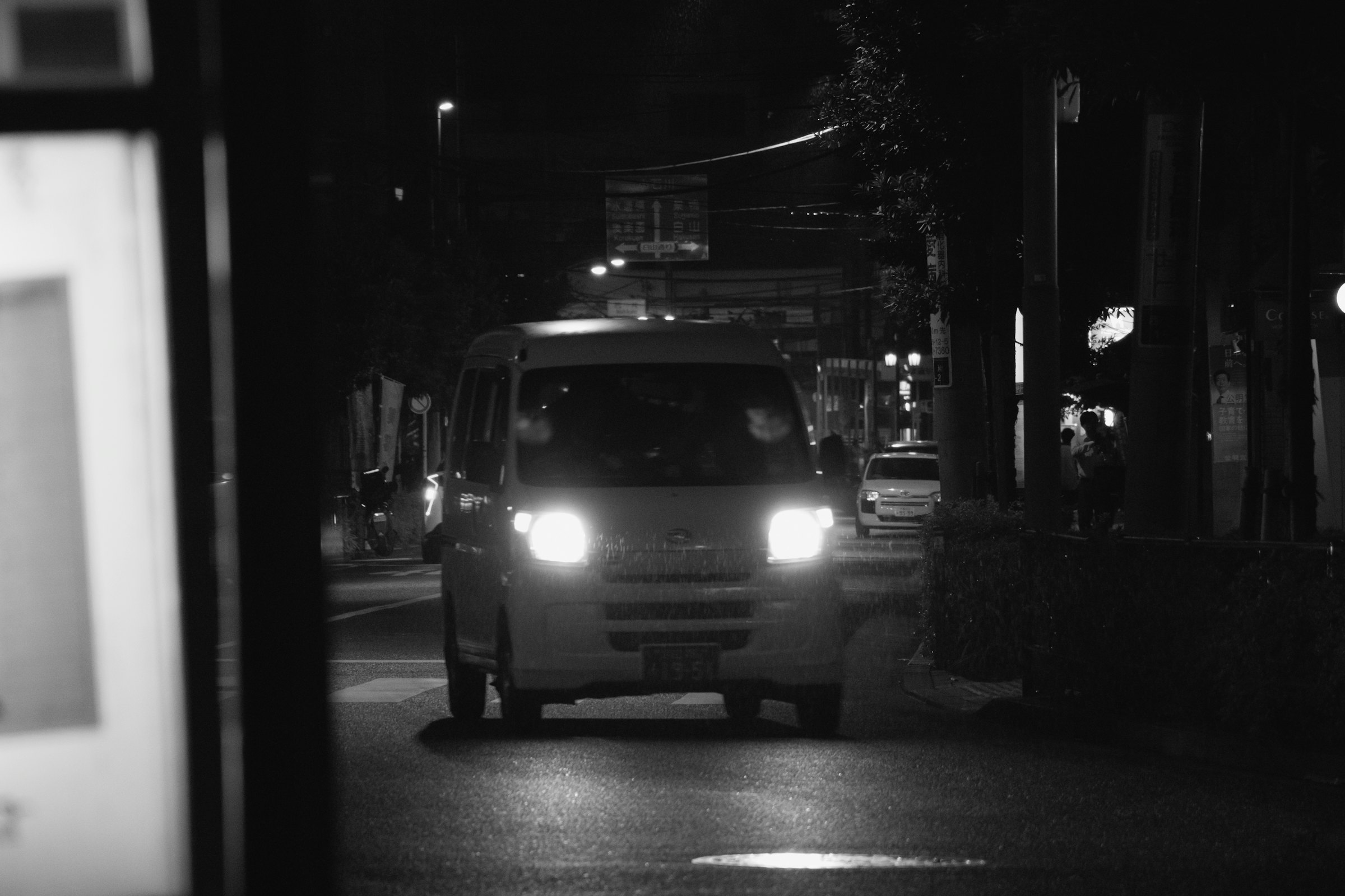 A van with its headlights on, parked on a city street at night.